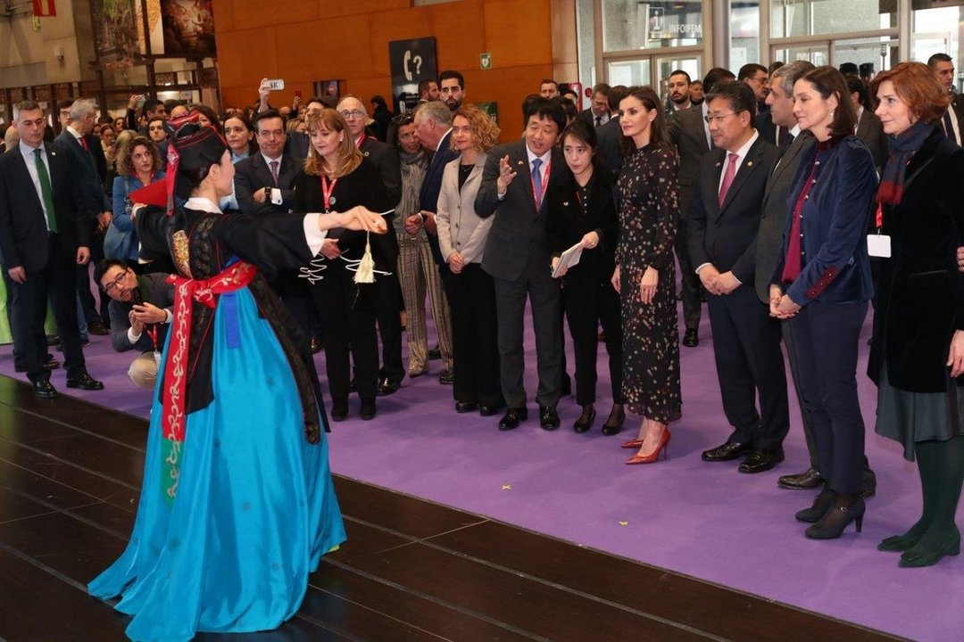 La reina observa una pieza de folclore coreano durante su paso por el stand de ese país asiático