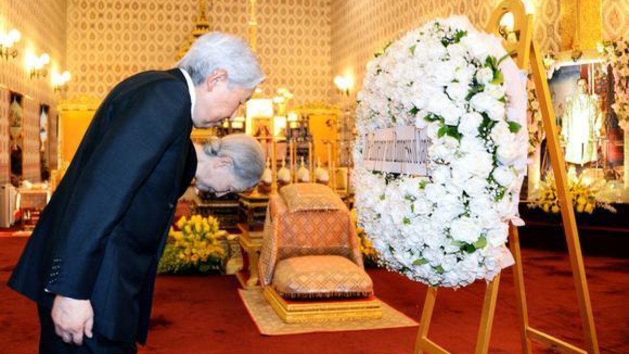 Akihito y Masako colocan una corona de flores junto al féretro del rey Bhumibol de Tailandia.